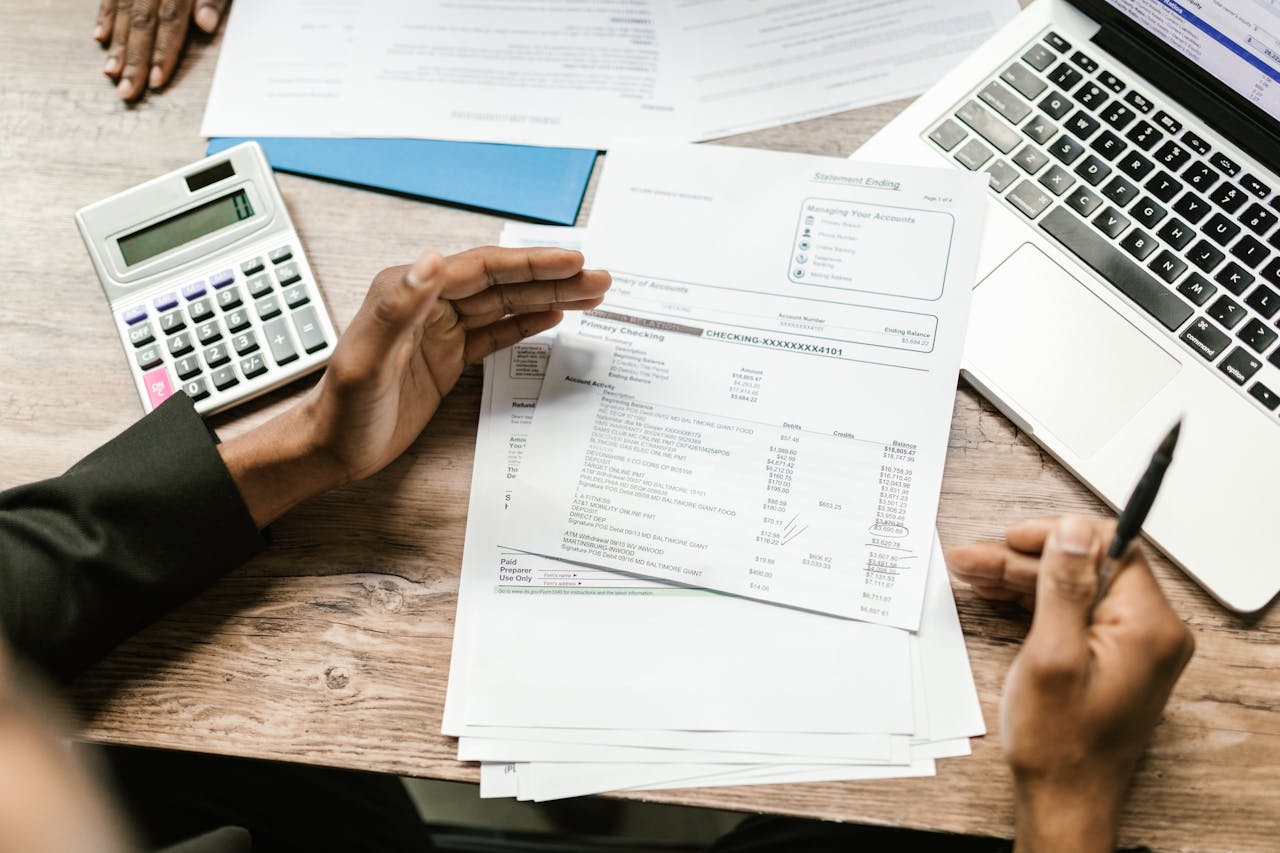 Paperwork, laptop, calculator on a table. Image by Pexels