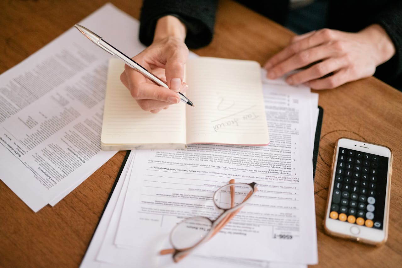 person writing on a paper. Fraud. Image by Pexels