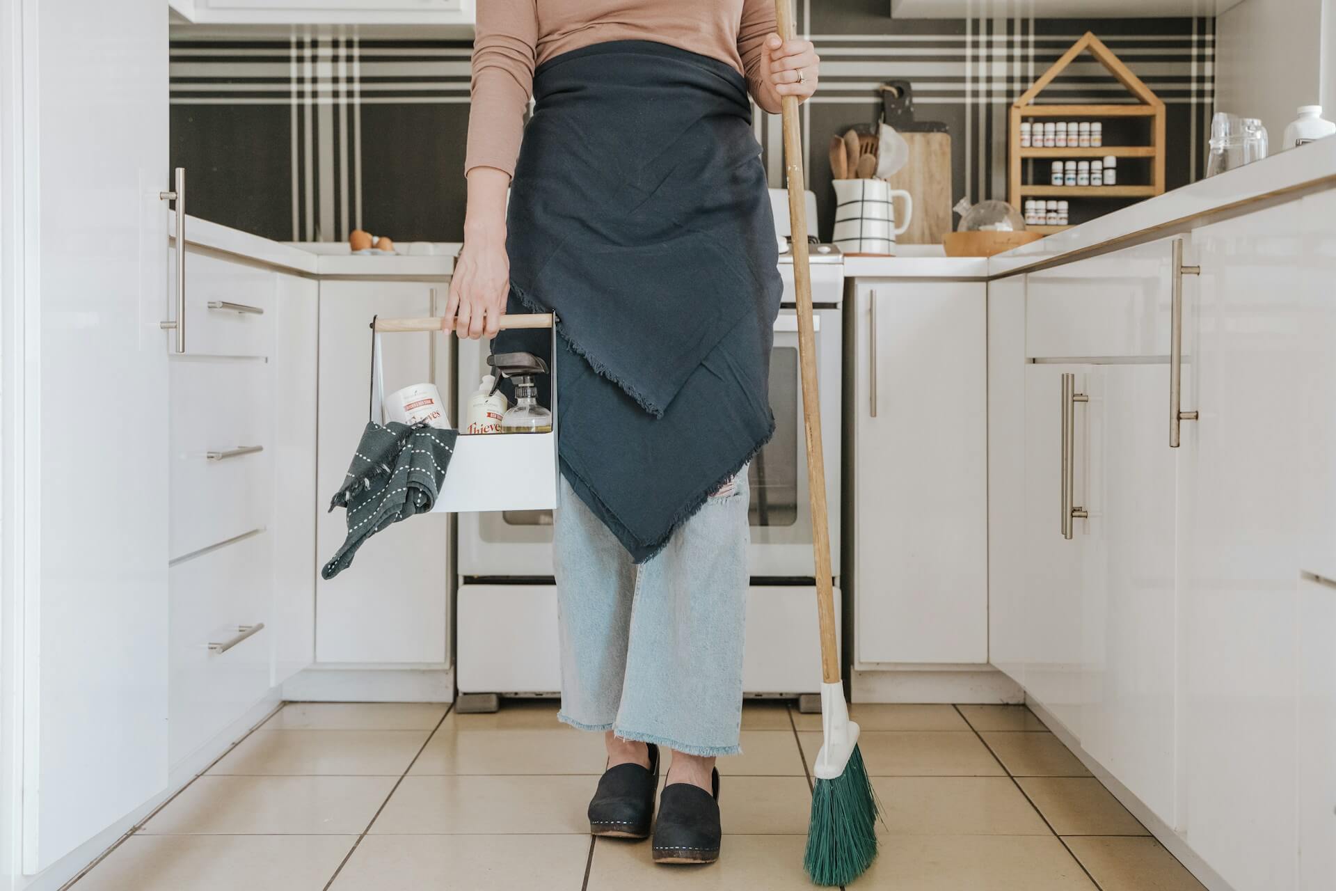 Person standing in a kitchen with cleaning supplies. Image by Unsplash