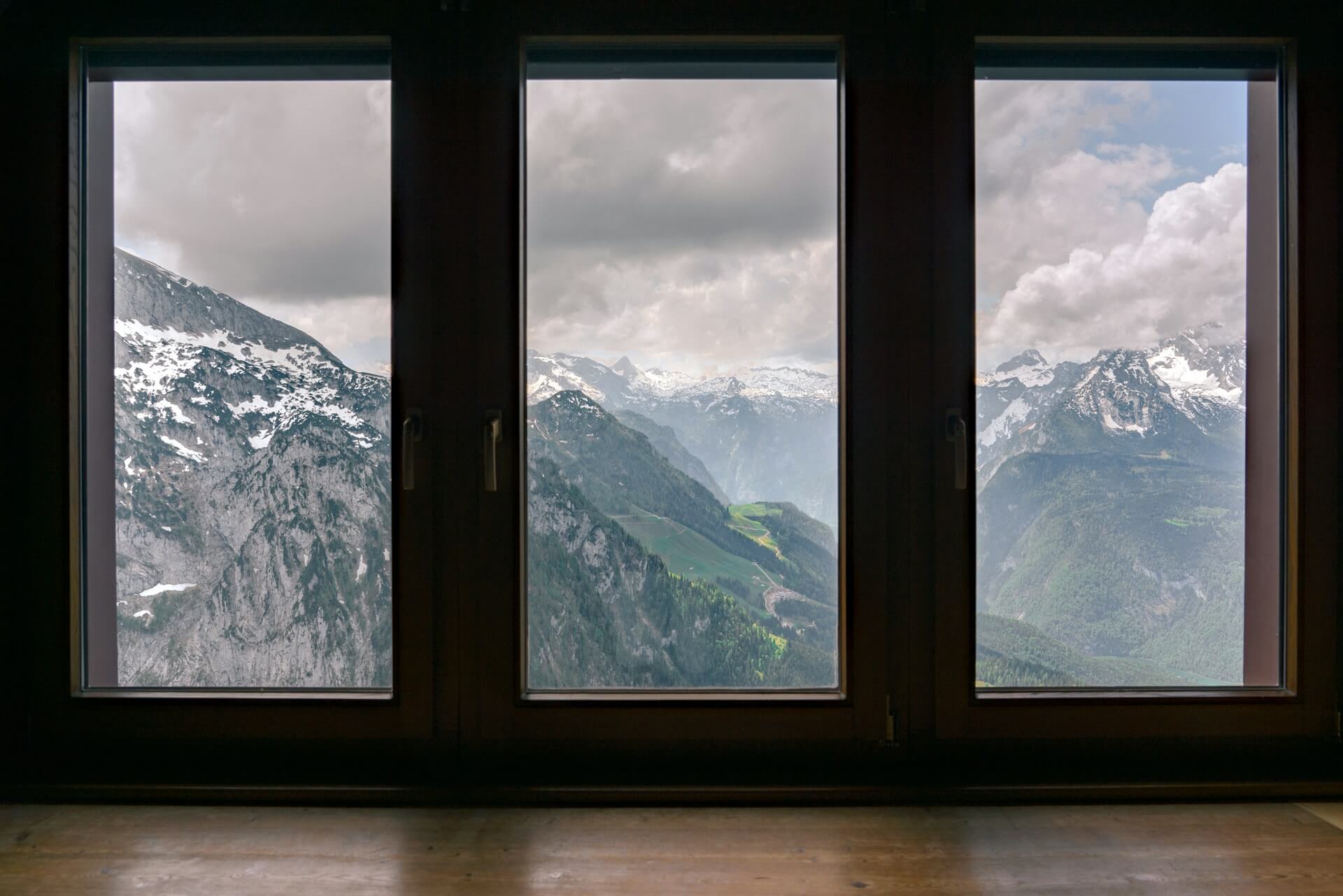 Fog-covered snow-capped mountain range view outside three large modern energy-efficient windows