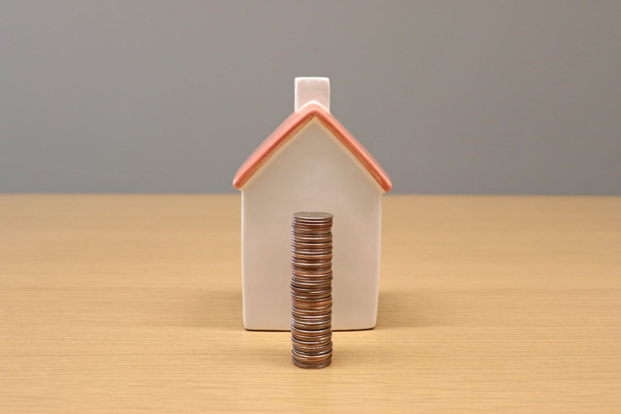 Stack of coins in front of a house. Image by Pexels