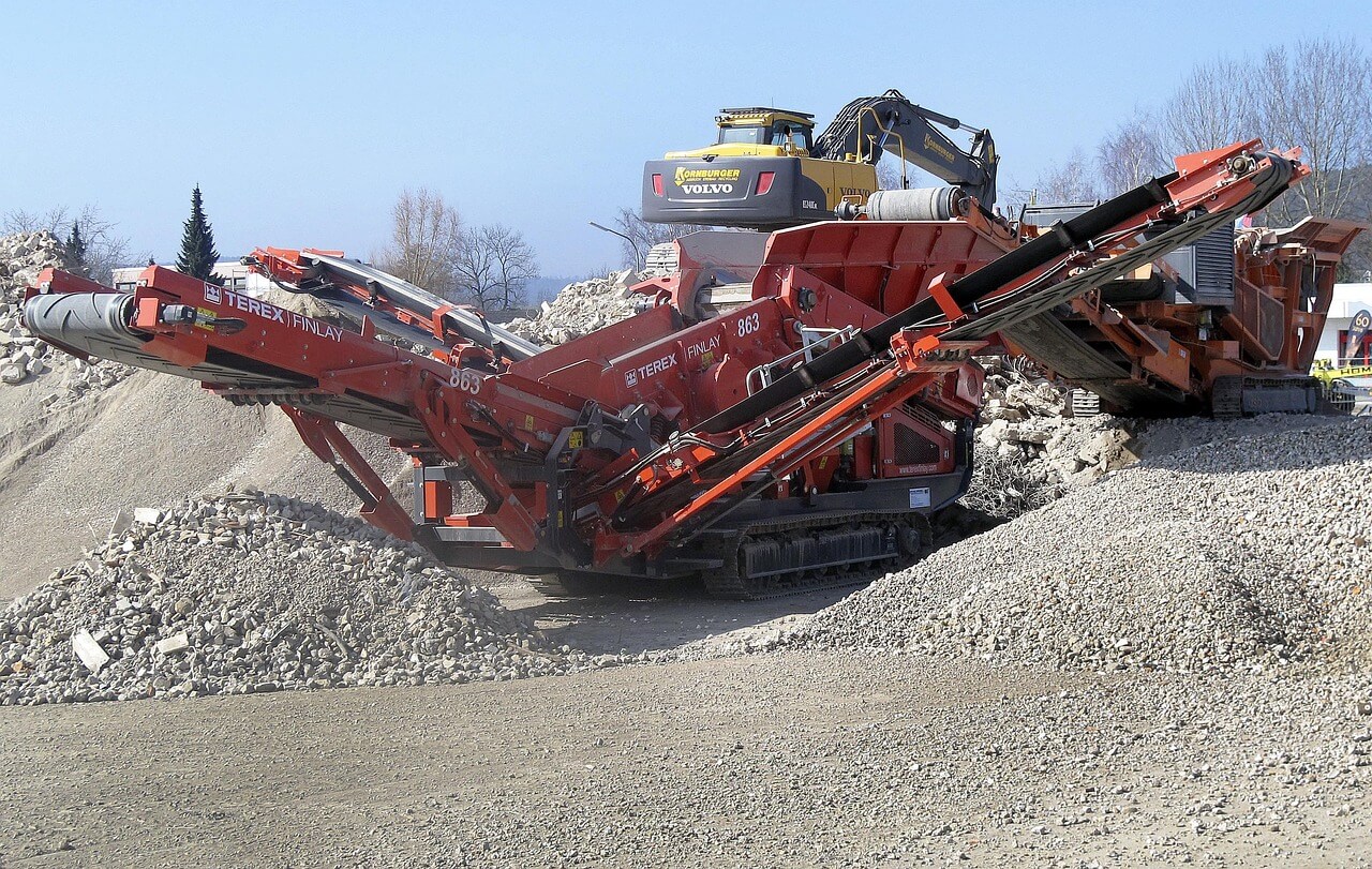 An excavator with a sorting grapple demolishing a building. Image by Pixabay