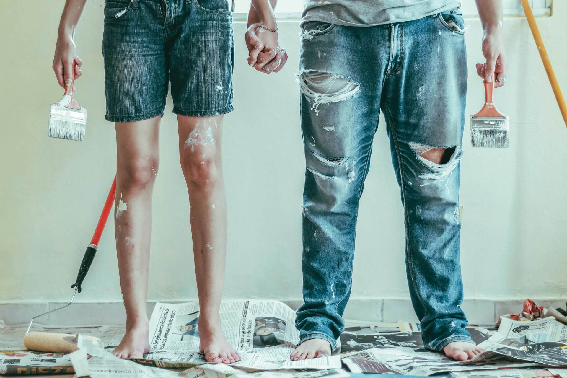 people holding paint brushes and holding hands