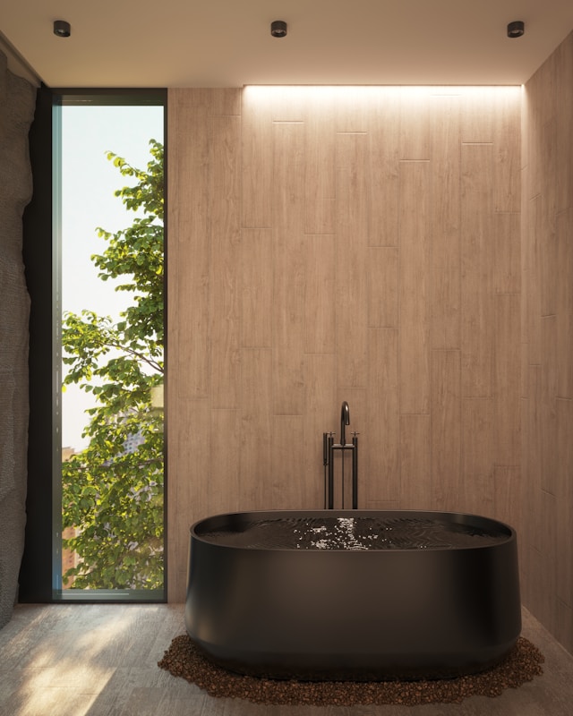 A large black bathtub sitting next to a window. Image by Unsplash