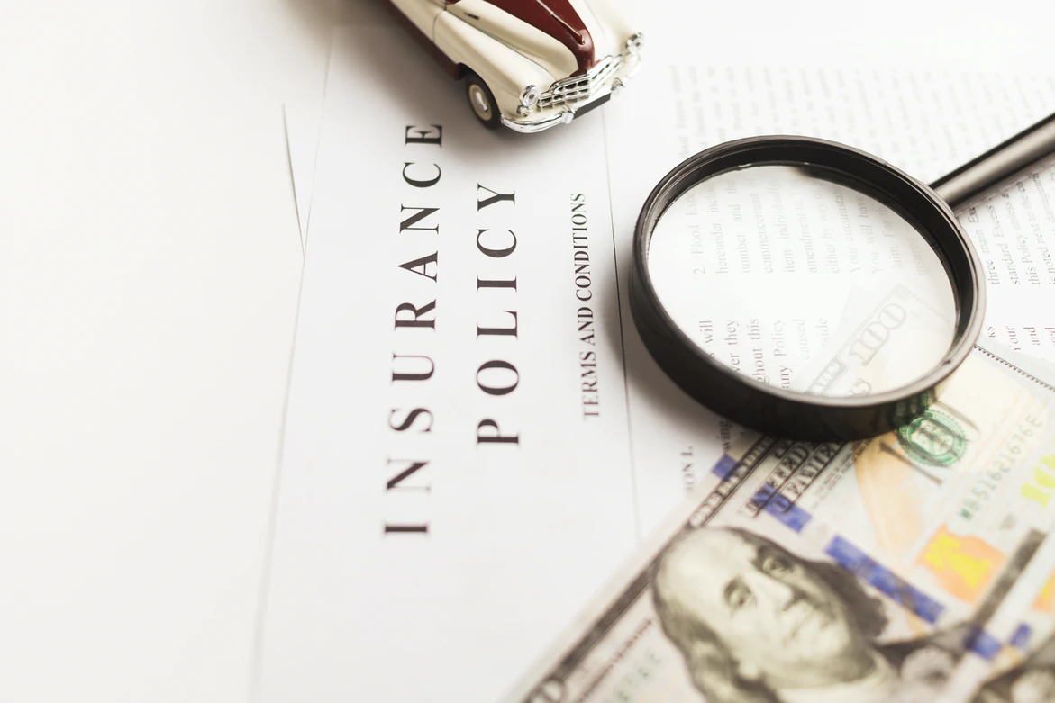 insurance policy paper, money, magnifying glas. Image by Unsplash