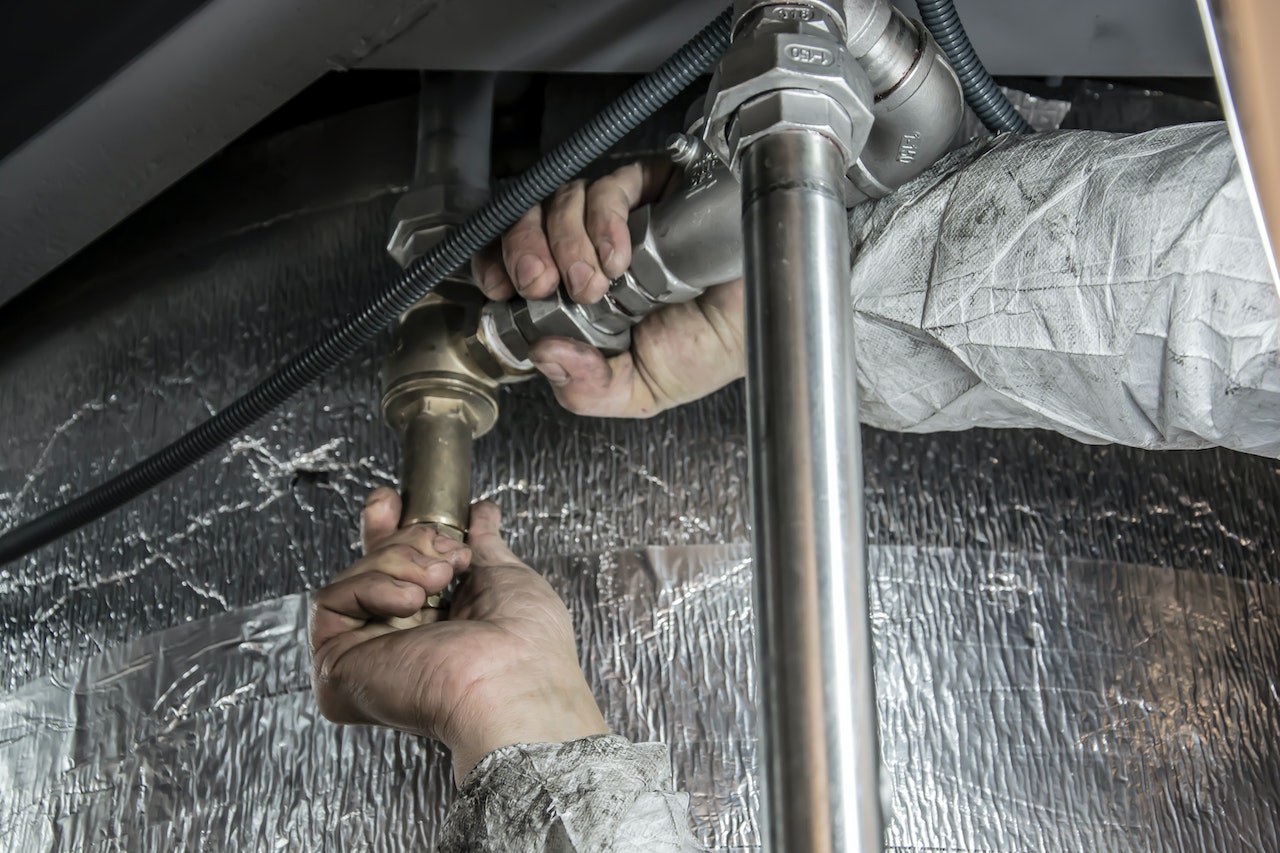 Plumber working on a pipe. Image by Pexels