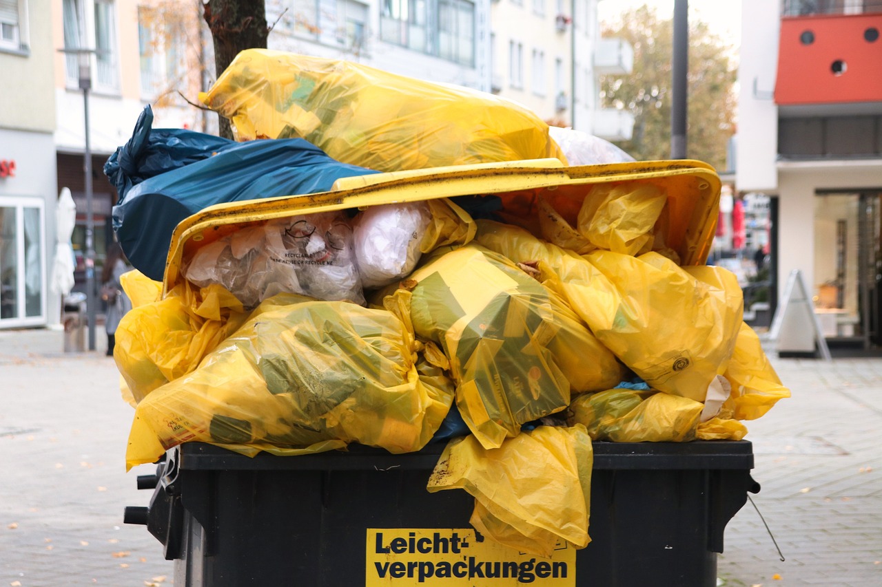 Dumpster with yellow trash bags. Image by Pexels