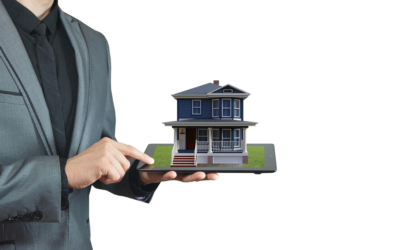 Person holding a blue house with a white fence around a porch. Image by Pixabay