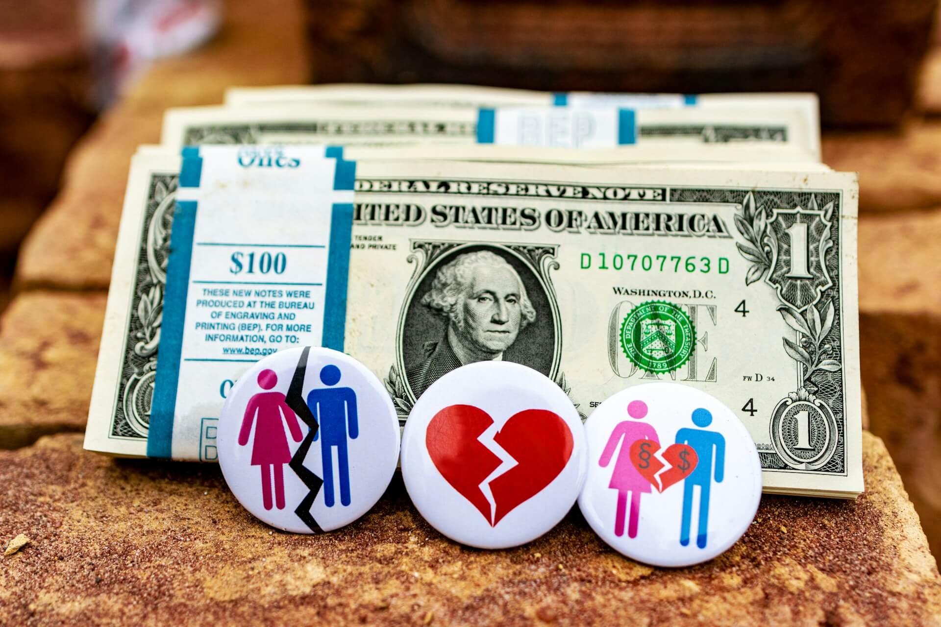 Buttons in front of piles of hundred dollar bills. Image by Unsplash