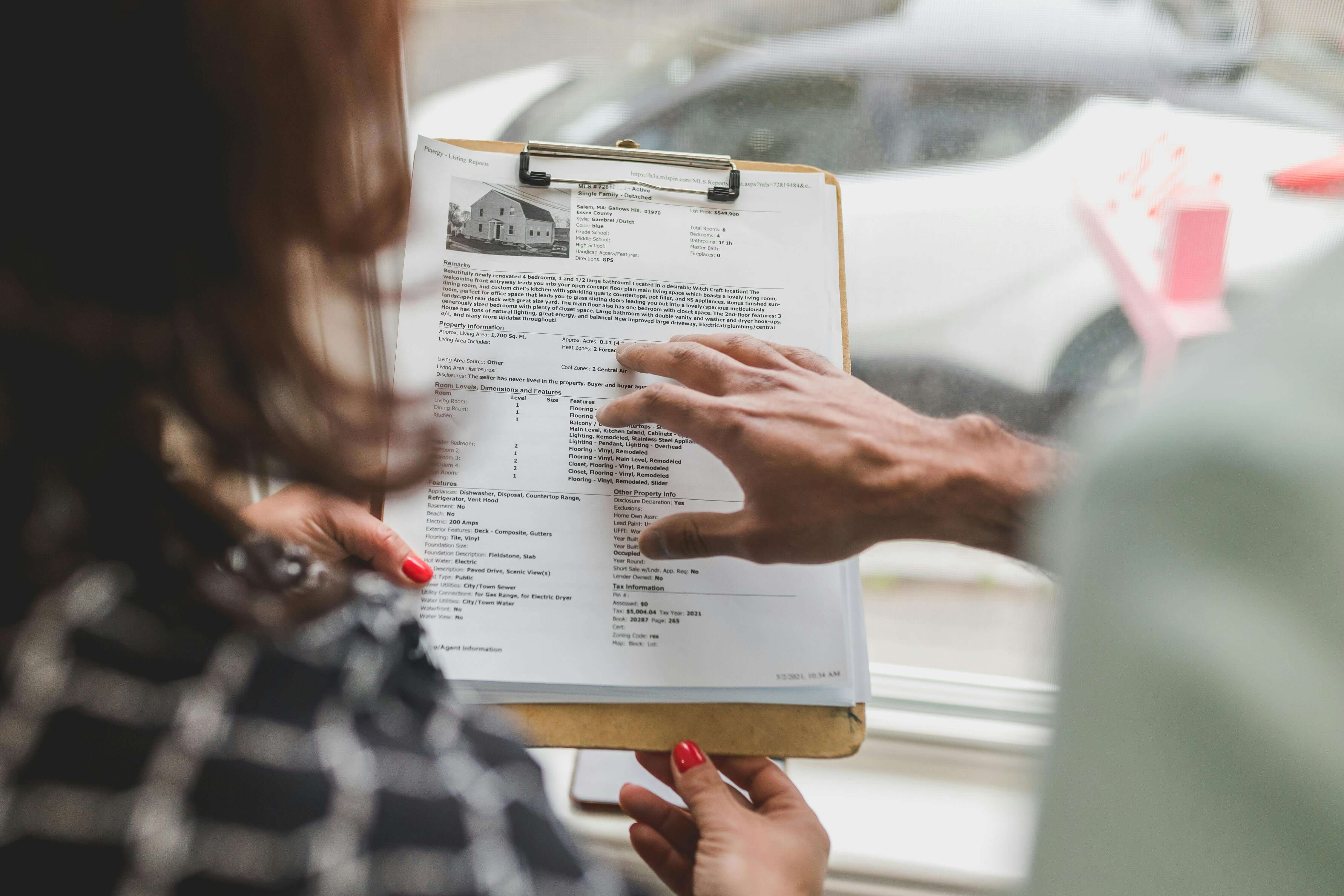 Two People looking at a for sale listing. Image by Pexels